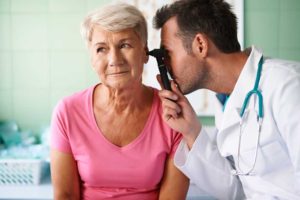 Doctor examining ear of senior woman